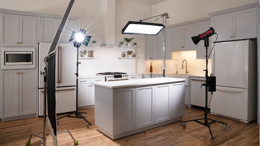 Professional kitchen photography studio with studio lighting, including softbox lights and reflectors. The setup features a well-organized kitchen counter, ideal for food photography and videography.