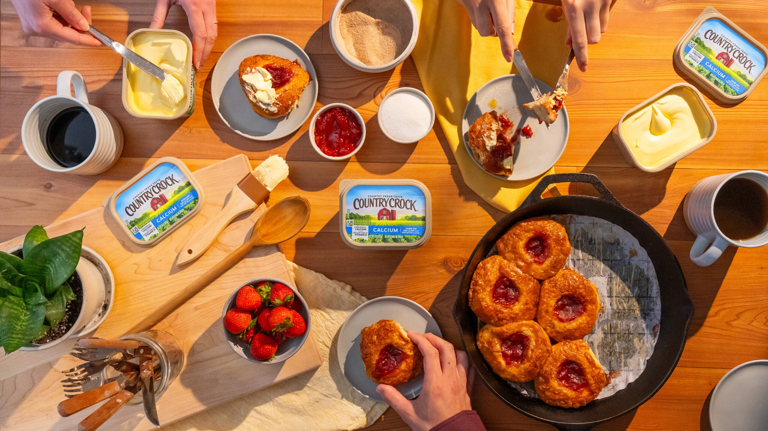 A beautifully set breakfast table featuring jammy biscuits, a popular CPG food product, fresh fruit, and hands skillfully using the product. Perfectly styled to highlight the vibrant colors and textures, this image captures the essence of a wholesome morning meal. Ideal for CPG food videography and photography showcasing delicious breakfast scenes.