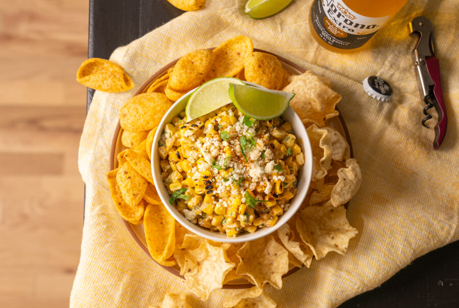 Vibrant bar scene featuring corn elote dip, tortilla chips, and a Corona beer. Ideal for showcasing your CPG brand's products through captivating food videography and photography. Enhance your marketing with visually engaging bar setups that attract and engage your audience.