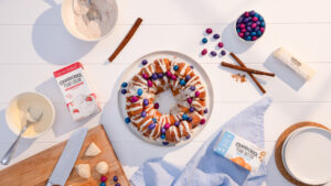 Easter monkey bread with expert food styling on a white surface, decorated with frosting, cinnamon and featured products.