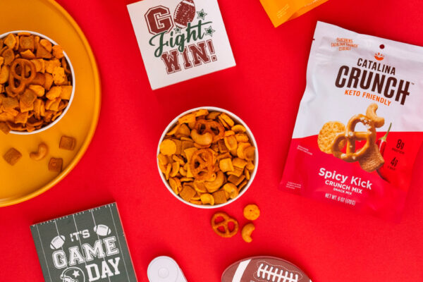 Game day snack mix with football-themed props, showcasing the product in a vibrant, bright red setting. Perfect for capturing the spirit of game day in food brand marketing.