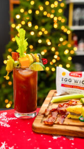 A loaded bloody mary decorated with a Christmas tree in the background to to highlight the use of product. 