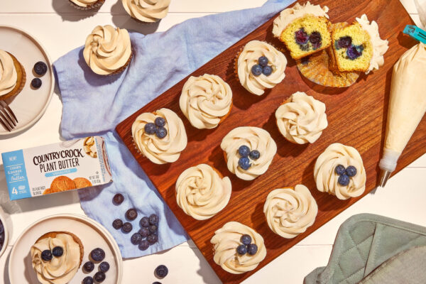 Beautiful blueberry cupcakes with harsh lighting on a wooden cutting board. Styled to look indulgent and capture the product featured.