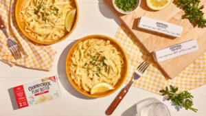 Dairy-free creamy pasta served in yellow bowls on a pristine white surface, tastefully styled to subtly highlight the featured product. Perfect for food CPG brands seeking enticing and visually appealing marketing visuals.