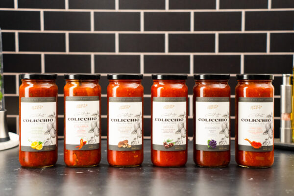 High End Pasta Sauces Pasta sauces elegantly lined up on a black surface against a tiled background, enhanced by professional studio lighting to showcase their variety and premium quality.