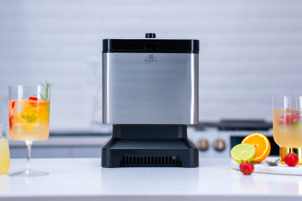 Ice machine in a stylish studio kitchen setting, illuminated with cool lighting. Artfully styled drinks prominently featuring the crystal-clear ice product.