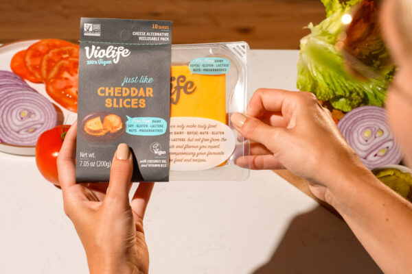 Violife Cheese in Studio Lighting Richly lit studio photo featuring a cheese product, expertly showcased with warm, inviting lighting and a professional hand model.