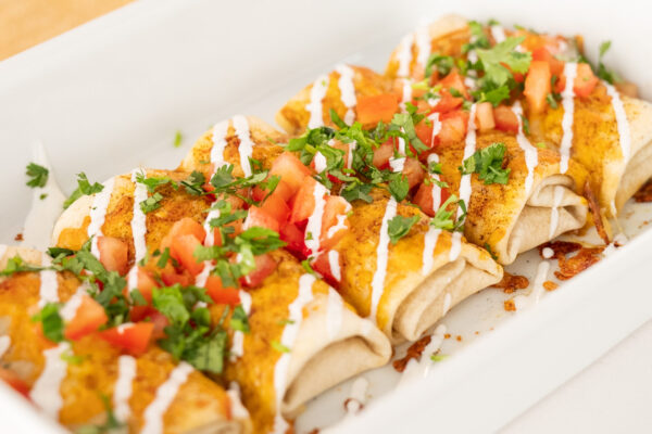 Cheese Topped Burritos Cheese-topped burritos in a white casserole dish, showcasing vibrant fresh ingredients and appetizing presentation.