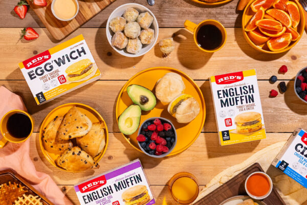 Full Breakfast Spread Expertly styled breakfast scene featuring croissants, donuts, fresh fruit, juice, and coffee, showcasing the featured CPG products in a warm and inviting setting on a wooden surface.