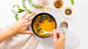 Squash soup topped with a drizzle of brown butter, crispy sage and sautéed mushrooms. On a food styled set with natural lighting to create an enticing dish scene.